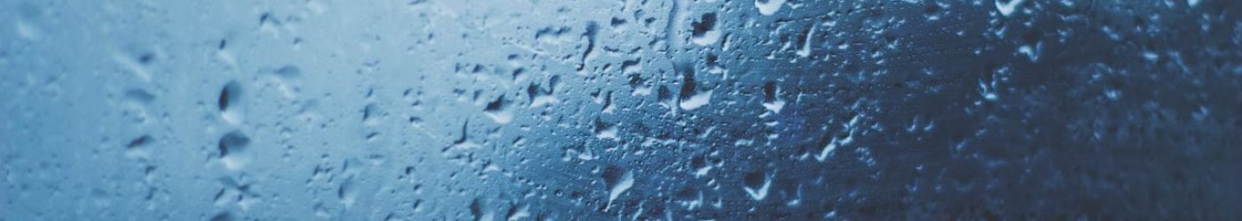 Detailed view of water droplets on a glass window with a blue background.
